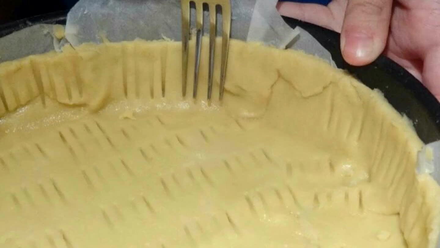 Dérouler la pâte dans un moule à tarte puis piquer le fond avec une fourchette et couper les bords.