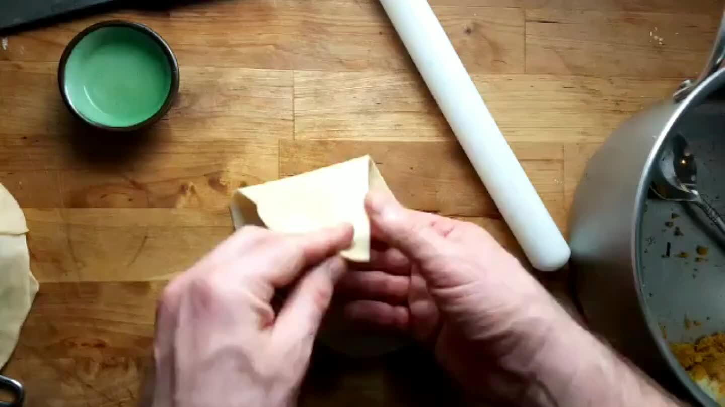 y coat half of the flat edge of the wrapper with water. Fold and pinch the moist portion over the dry portion to form a cone. Pinch the tip to seal it.