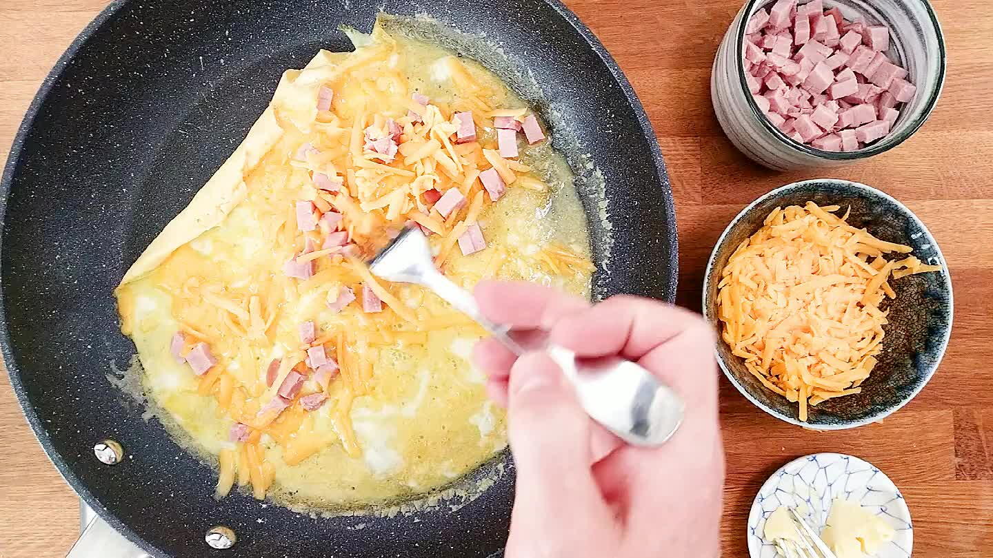 the egg from one edge of the pan, guiding it to rollover itself and down the pan.
