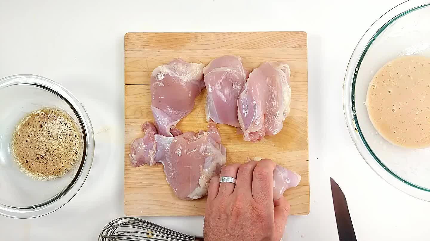 Taglia le cosce di pollo a pezzi e aggiungile alla marinatura con l'amido di mais aggiunto.