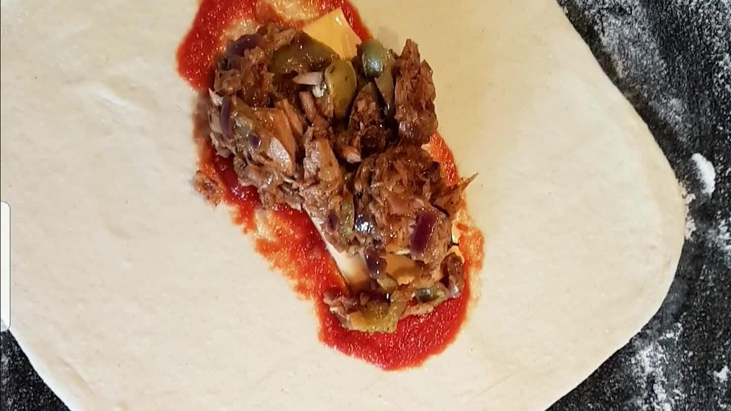 s. Rol het deeg uit met de deegroller naar een vierkantje. Smeer met een theelepel een streep tomatenpuree op het deeg. Leg er een (1/2) plakje cheddar kaas op, schep daarboven op wat tonijnmengsel. Vouw de zijkanten erover dan de achterkant en rol het broodje op het laatste flapjes deeg.