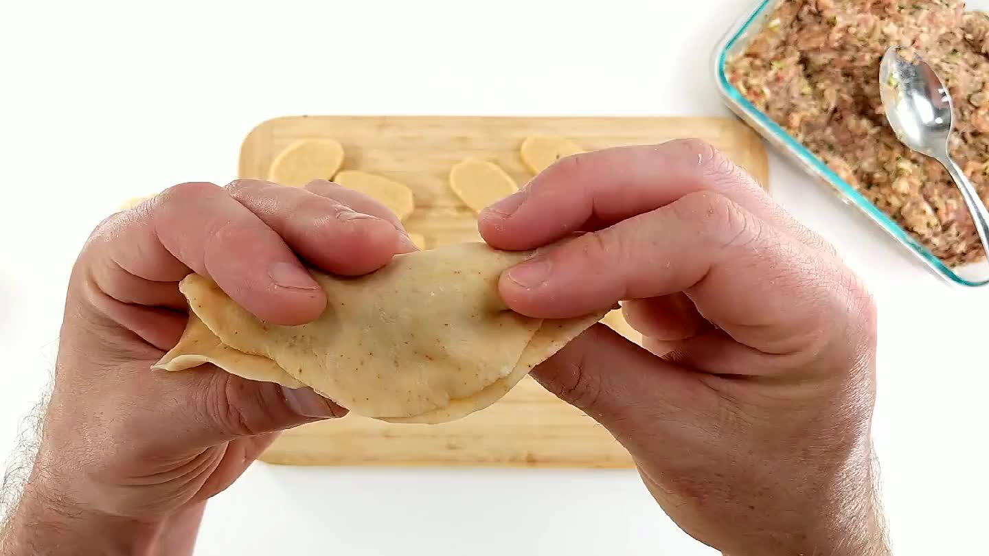 do premi e piega dei ravioli cinesi. Chiudere l'impasto, poi premere formando circa 5 pieghe lungo il bordo. Si possono trovare molte tecniche di chiusura dei dumpling su youtube. A me piace anche la chiusura in stile pechinese. Date un'occhiata alla ricetta qui sotto.