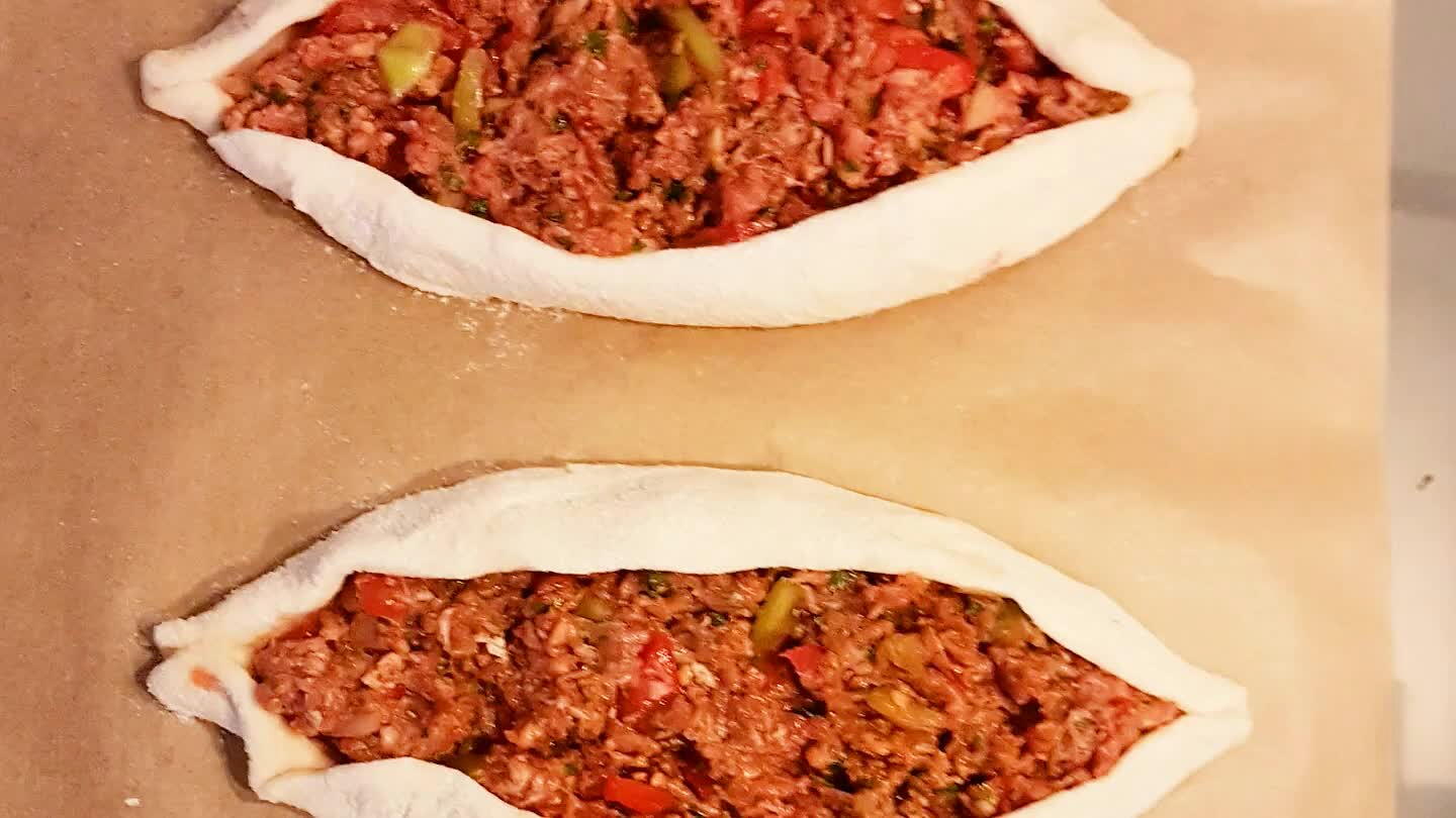 n deegroller het bolletje uit naar een langwerpige plak. Verdeel het gehakt over de lengte en vouw de randjes omhoog, zodat het lijkt op een kano. Bestrijk de randjes deeg met ei en besprenkel met sesamzaad