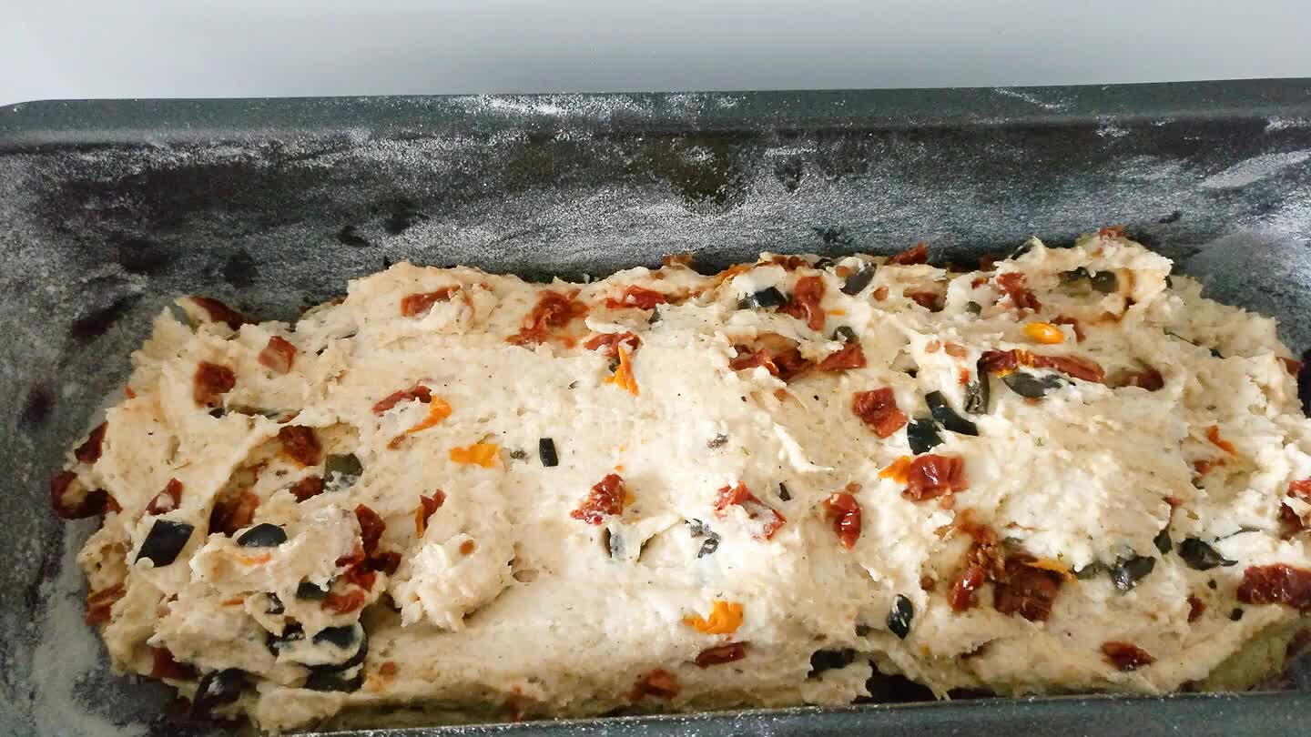 añadimos el harina, aceite, un poco de sal y mezclamos. Luego añadimos el agua con la levadura y amasamos hasta que la masa casi se despegue de los dedos. Por ultimo añadimos las aceitunas y el tomate y amasamos hasta que este bien distribuido en la masa. Tomamos un bol alargado de 25cm de largor. Lo engrasamos y le espolvoreamos harina. Distribuimos la masa del pan y dejamos reposar en un lugar calido 45 min.