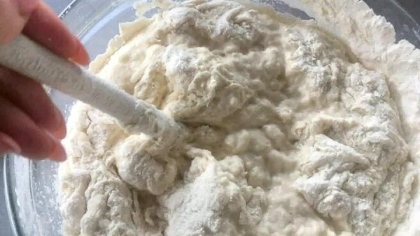 číme si ruky do vody, aby sa nám nelepilo cesto a cesto uchopíme v strede. Vytiahneme ho dohora, aby sa natiahlo.Potom cesto položíme a preložíme na polovicu.