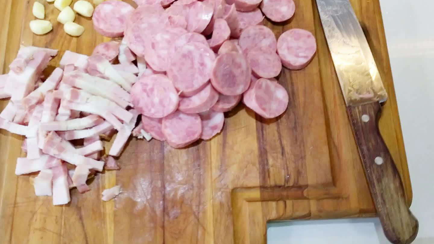 são que o feijão será cozido, adicione o alho amassado e o azeite, mexa até dourar. Em seguida refogue o bacon e a calabresa por aproximadament uns 2~3 minutos.