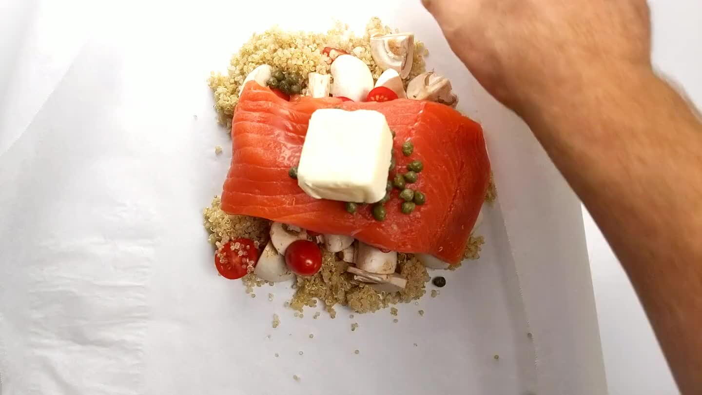 continue along the open side of the parchment, folding/rolling the edge in towards the contents until you get to the opposite corner. Tuck the opposite corner under the roll. Now you can repeat with remaining salmon.