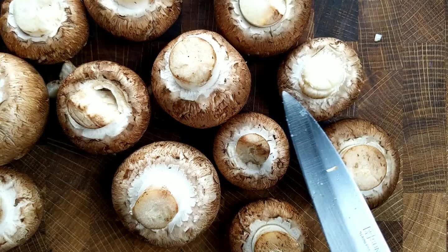 . Then, slice away any tough or darkened portions of the mushroom stems. Group the mushrooms into a grid, stem facing upwards. Slice first in half, then into quarters.