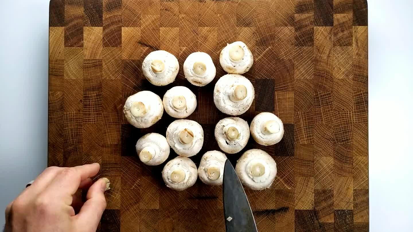 . Then, slice away any tough or darkened portions of the mushroom stems. Group the mushrooms into a grid, stem facing upwards. Slice first in half, then into quarters.