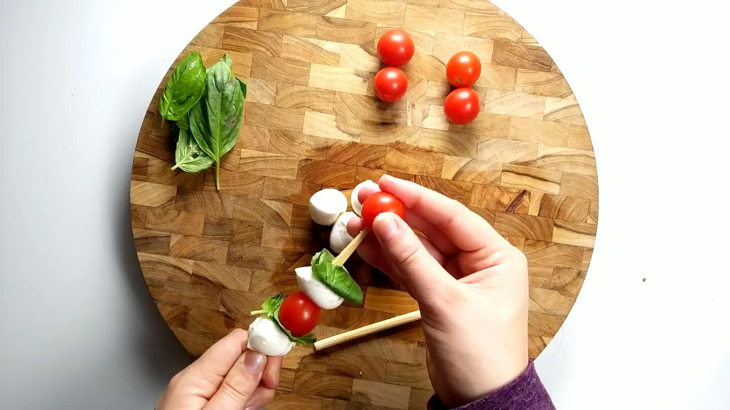 Add a ball of mozzarella, and then fold a piece of basil on top. Add a tomato to top it off and repeat.