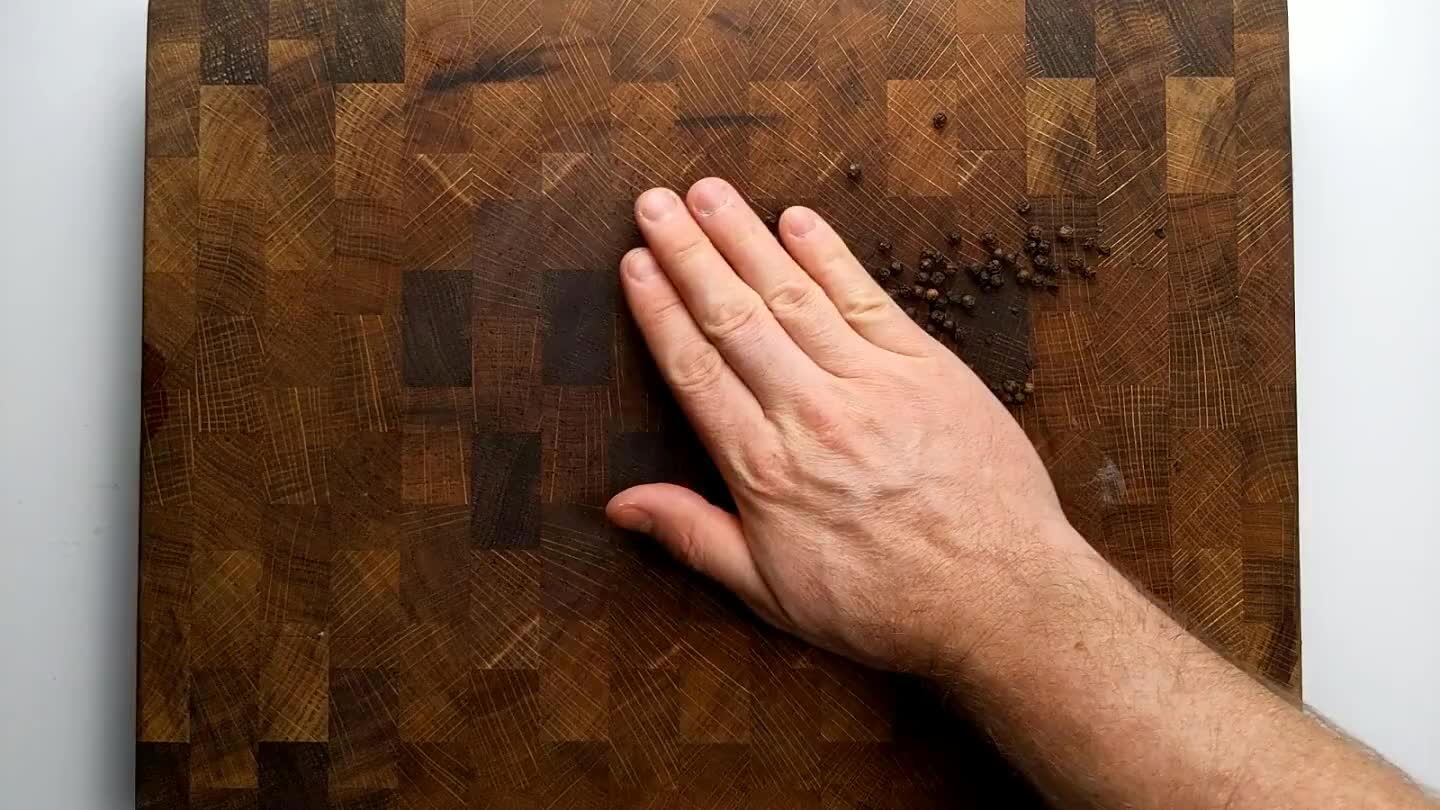 heavy pan works well if you put your weight into it. Or use a mortar and pestle or a meat tenderizer. You don't want to grind the peppercorns, just crack them.