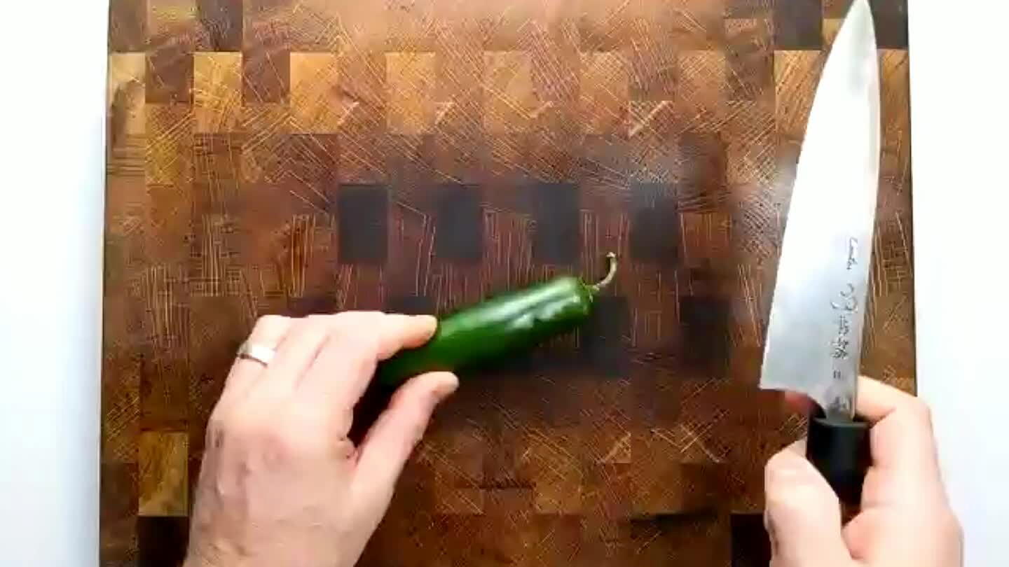 echniques. It's very satisfying. Cut off the stem tip. Slice the chile in half. Remove the seeds. Slice the halves into strips, as thin as possible. Group the strips and slice into tiny little cubes.