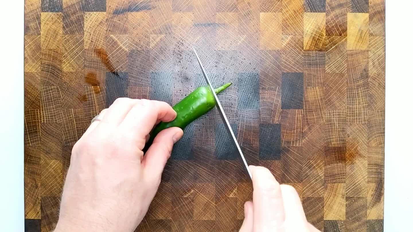 echniques. It's very satisfying. Cut off the stem tip. Slice the chile in half. Remove the seeds. Slice the halves into strips, as thin as possible. Group the strips and slice into tiny little cubes.