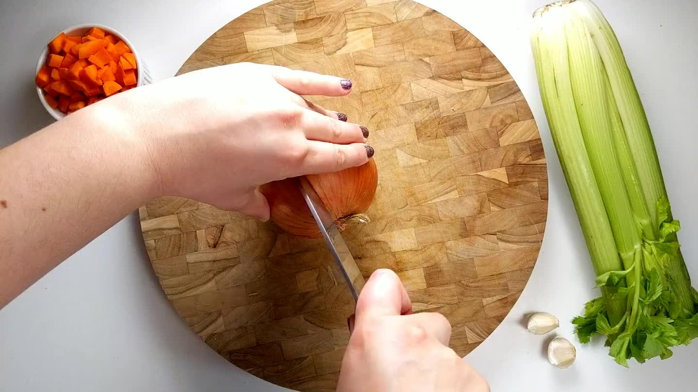 the cutting board, cut the onion in half, leaving the root side intact. Then slice thin strips across the onion toward the root. Chop perpendicularly to create the dice.