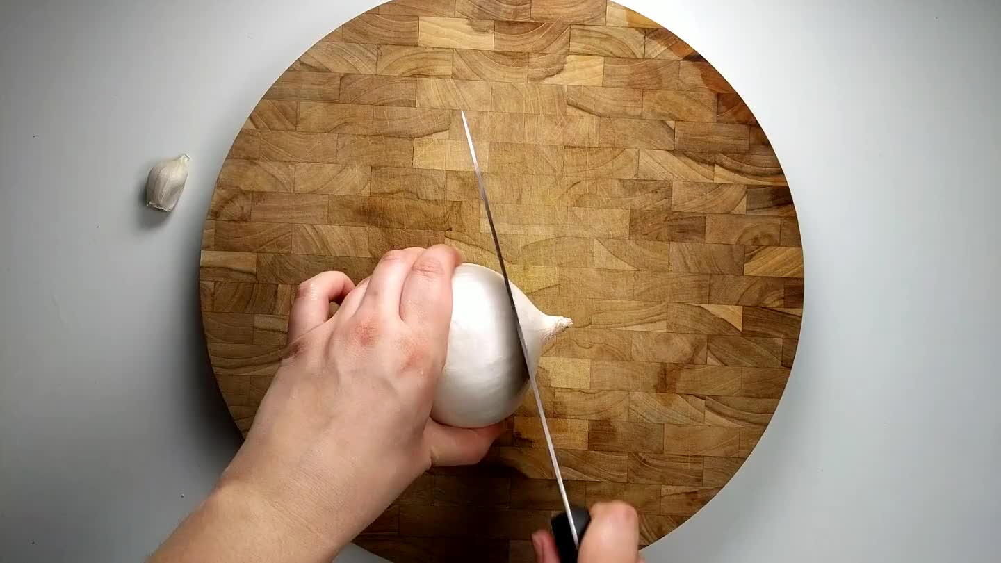 the cutting board, cut the onion in half, leaving the root side intact.