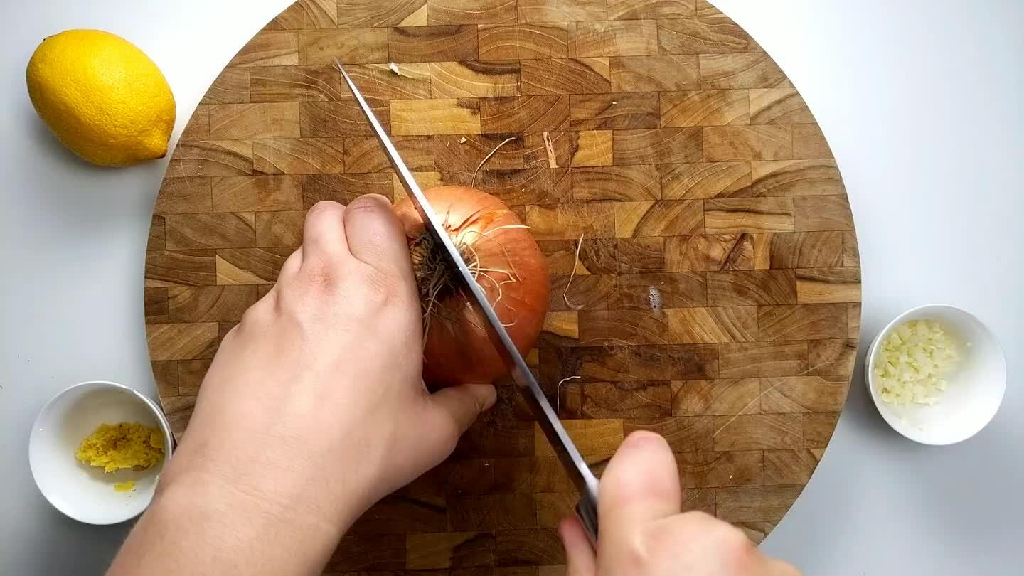 ing the root side in-tact. Using the knife parallel with the cutting board, make two cuts into the open face of the onion.