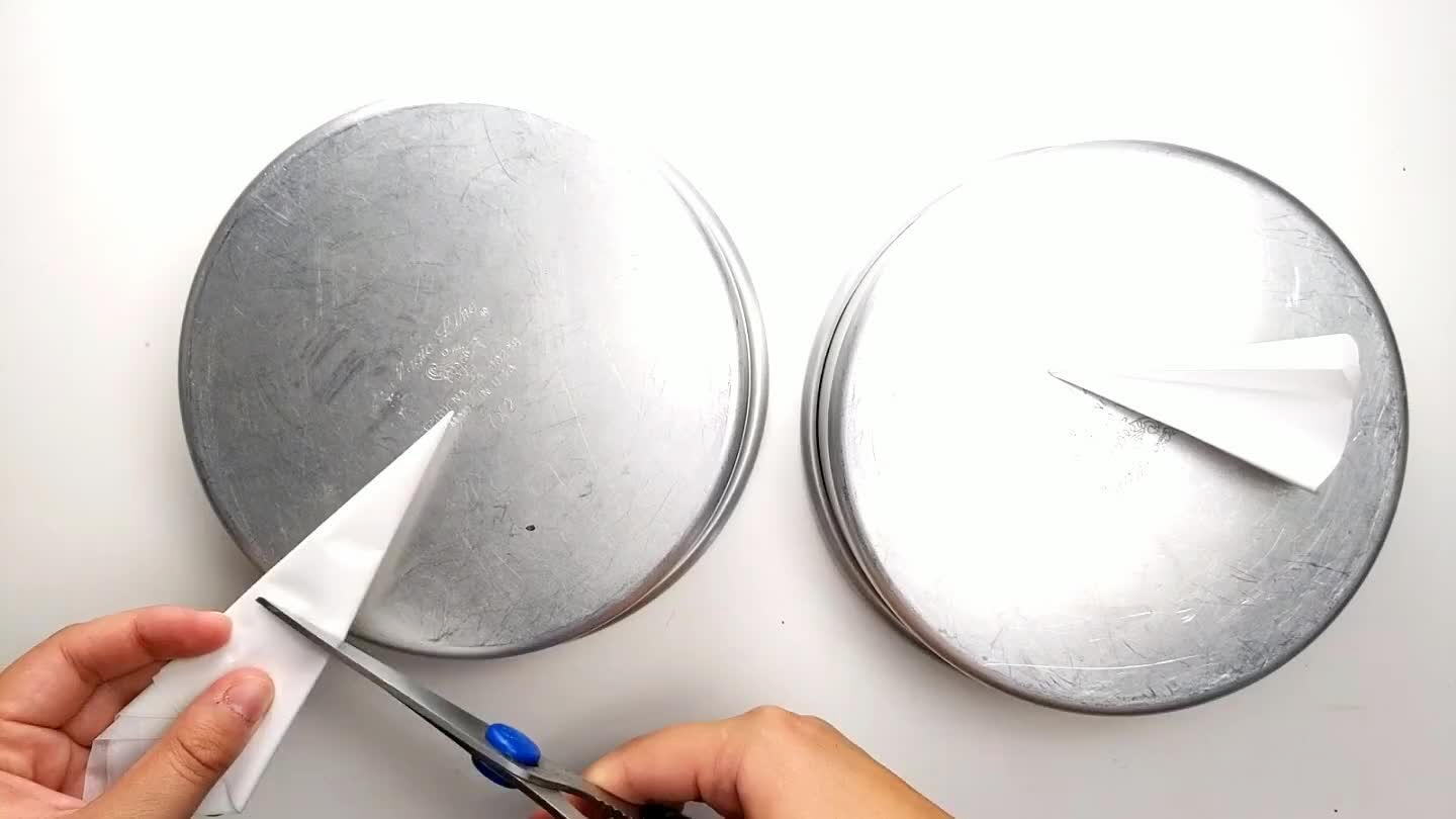 the size and cut. Unfold the piece of parchment and use oil spray to stick it to the bottom of the pan. Repeat for both pans and spray the sides with the oil.